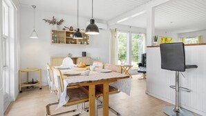 Un'ampia sala da pranzo con tavolo in legno, sedie e lampade a sospensione.