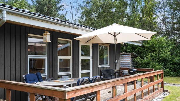 Una terrazza con tavolo e sedie, un barbecue e un ombrellone.