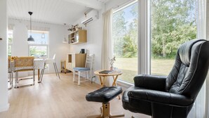 Un soggiorno moderno con un divano in pelle nera, un tavolo da pranzo in legno e una grande finestra con vista sull'esterno.