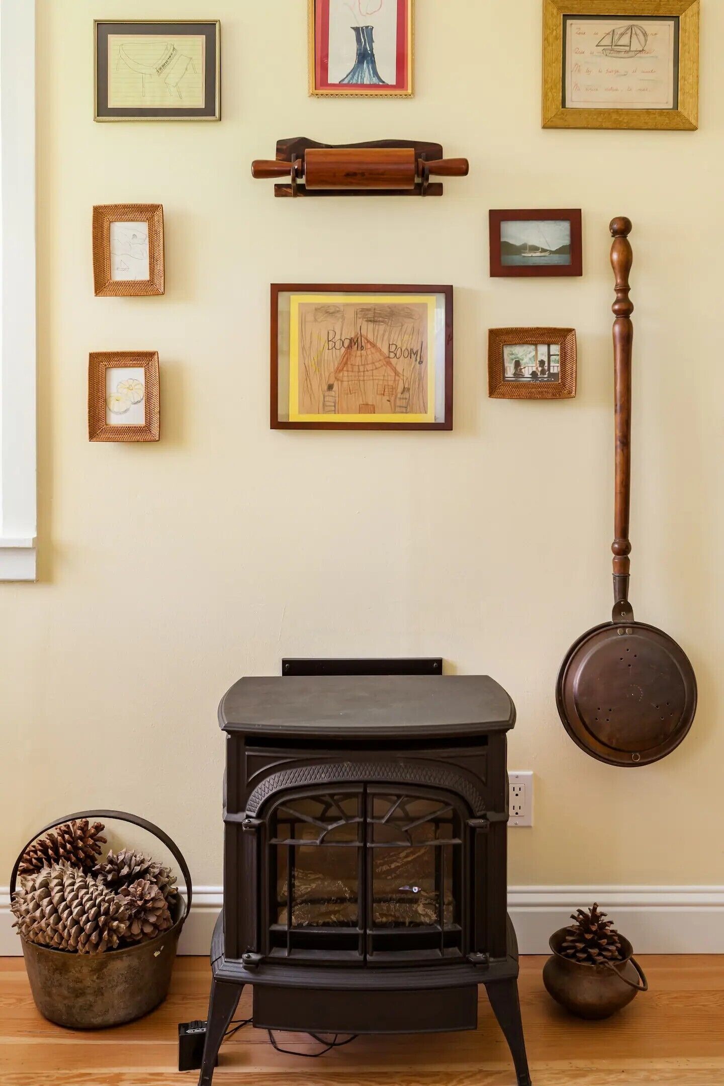 Une pièce chaleureuse avec un poêle à bois, des œuvres d’art encadrées accrochées au mur et une décoration en forme de pomme de pin.