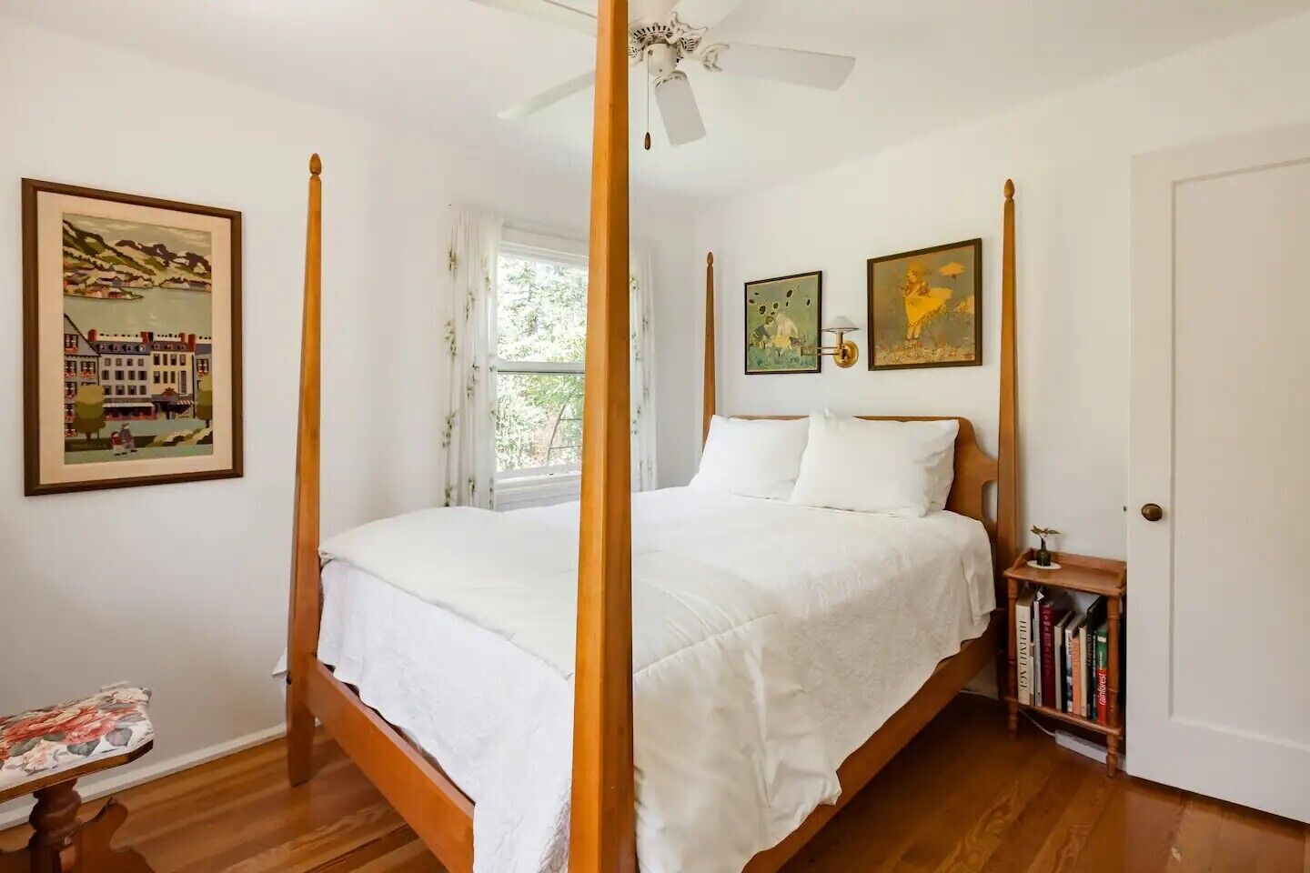 A bedroom with a four-poster bed, a ceiling fan, and a bookshelf with books.