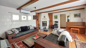 A spacious living room with a fireplace, a sofa, a dining table, and a bench. - Beautiful home in Höör with sauna (Höör)