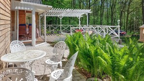 A patio with white metal furniture, a pergola, and lush greenery. - Beautiful home in Höör with sauna (Höör)