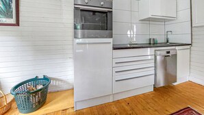 A compact kitchen with white cabinets, a stainless steel oven, a dishwasher, and a small countertop. - Beautiful home in Höör with sauna (Höör)