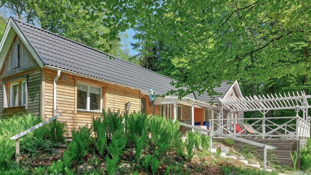 A wooden cabin with a covered porch and a white fence. - Beautiful home in Höör with sauna (Höör)