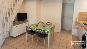 Un espacio habitable compacto con comedor, televisor, lavadora y escalera.