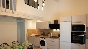 Una cocina compacta con lavadora, horno empotrado y microondas.