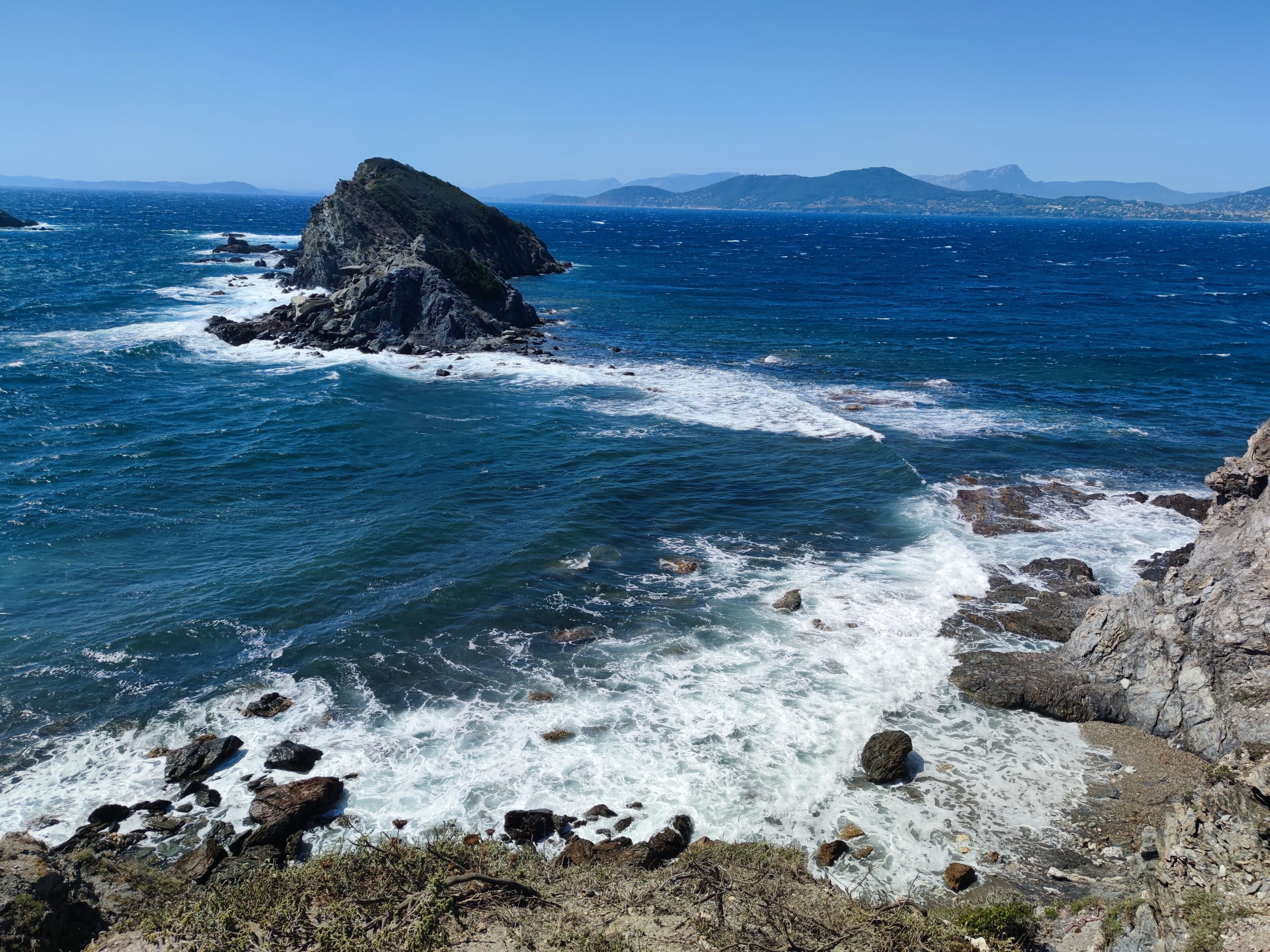 A coastal landscape with rocky terrain and a clear view of the sea.
