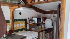A compact kitchen with a stove, microwave, and various kitchen items on shelves. - Cabano for rent by the sea  (Hyères)