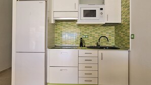 A compact kitchen with white cabinets, a microwave, and a sink. - A009 Seaside view Las Vistas TRG Tenerife Royal Gardens (Playa de las Américas)