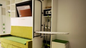 A compact room with a bed, a small table, a cabinet, and a shelf with a basket. - A009 Seaside view Las Vistas TRG Tenerife Royal Gardens (Playa de las Américas)