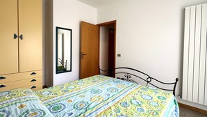 A bedroom with a bed, wardrobe, mirror, and radiator. - M397 - Marcelli, delightful three-room apartment 200m from the sea (Marcelli)