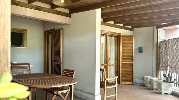 A dining area with a wooden table and chairs, a window with a view, and a door with a curtain. - M397 - Marcelli, delightful three-room apartment 200m from the sea (Marcelli)