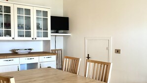 A dining area with a wooden table and chairs, a kitchen with white cabinets and a television. - M397 - Marcelli, delightful three-room apartment 200m from the sea (Marcelli)