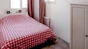 Une chambre à coucher avec une couvre-lit à carreaux, un radiateur et une porte.