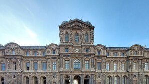 Un grand bâtiment historique à l’architecture classique, caractérisé par de nombreuses fenêtres en arc et des statues.