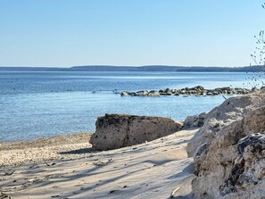 Un paisaje costero con costa rocosa, mar tranquilo y colinas al lejano.