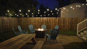 Un patio al aire libre con un brasero, sillas de madera y una mesa.