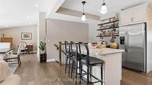 Una cocina moderna con una isla central, taburetes de bar y un refrigerador de acero inoxidable.