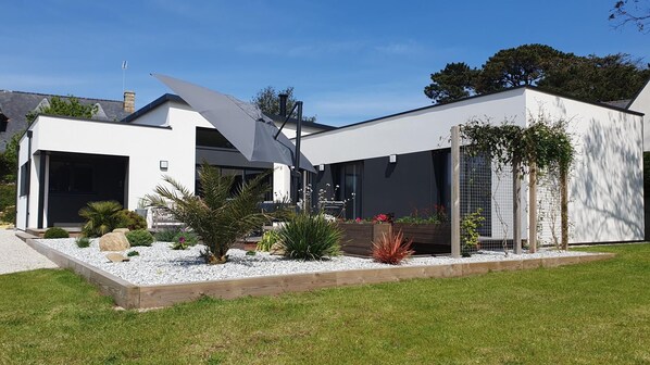 A modern two-story house with a garage, a covered patio, and a well-maintained garden.