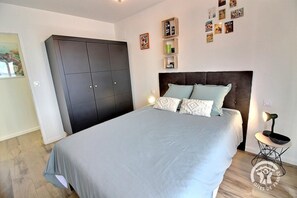 A bedroom with a bed, a wardrobe, and a bedside table with a lamp.