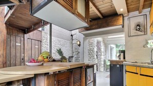 A kitchen with wooden cabinets, a stone wall, and a built-in refrigerator. - Echappée Breizh - Saint Pierre Quiberon (SAINT PIERRE QUIBERON)