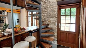 A kitchen with a bar area, wooden stools, and a stone accent wall. - Echappée Breizh - Saint Pierre Quiberon (SAINT PIERRE QUIBERON)