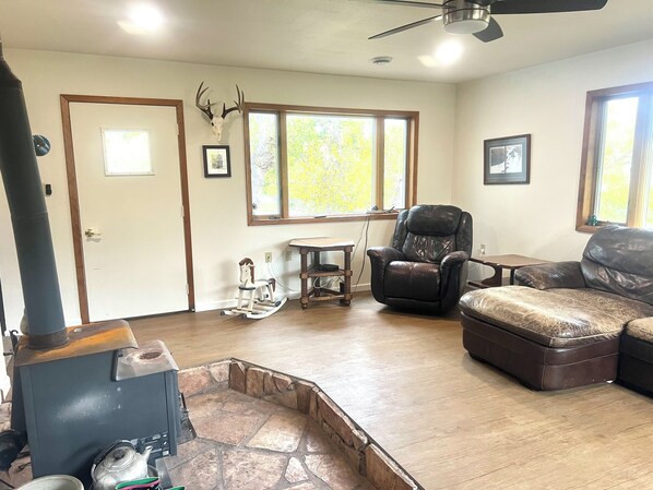 A living room with a fireplace, a rocking horse, a leather recliner, and a stone fireplace surround. - Cascade Home on the Missouri- Fishing Retreat (Cascade)