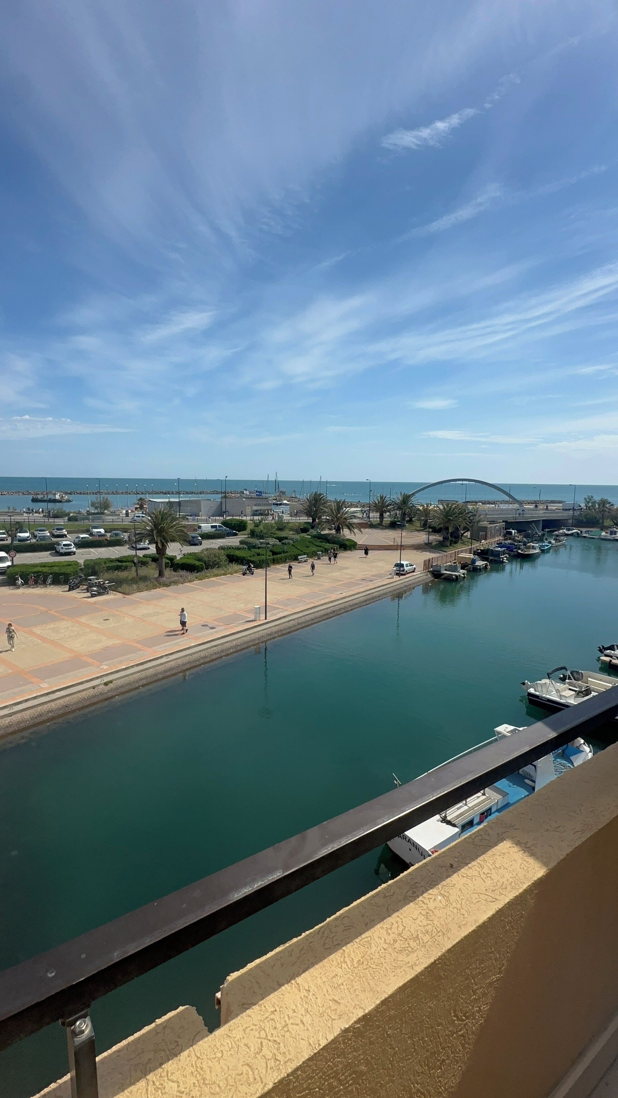 A marina with boats docked, a clear sky, and a distant bridge.