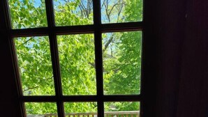 Une vue à travers une fenêtre avec une porte en bois, dévoilant une terrasse avec des meubles d’extérieur et une rambarde.