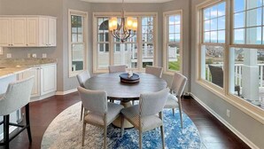 A dining area with a round table, striped chairs, and a chandelier.