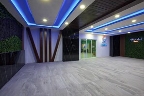 Experience the sleek, open lobby of Playa Azul Resort, featuring a spacious floor plan, a reception desk, and a unique green wall.