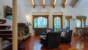 A spacious living room with a fireplace, comfortable seating, and large windows offering views of the outdoors.