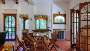 A dining area with a stone fireplace, wooden chairs, and a tiled floor.