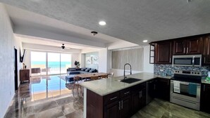 Una cucina moderna con mobili in legno scuro, un'isola ampia con lavello ed elettrodomestici in acciaio inossidabile.