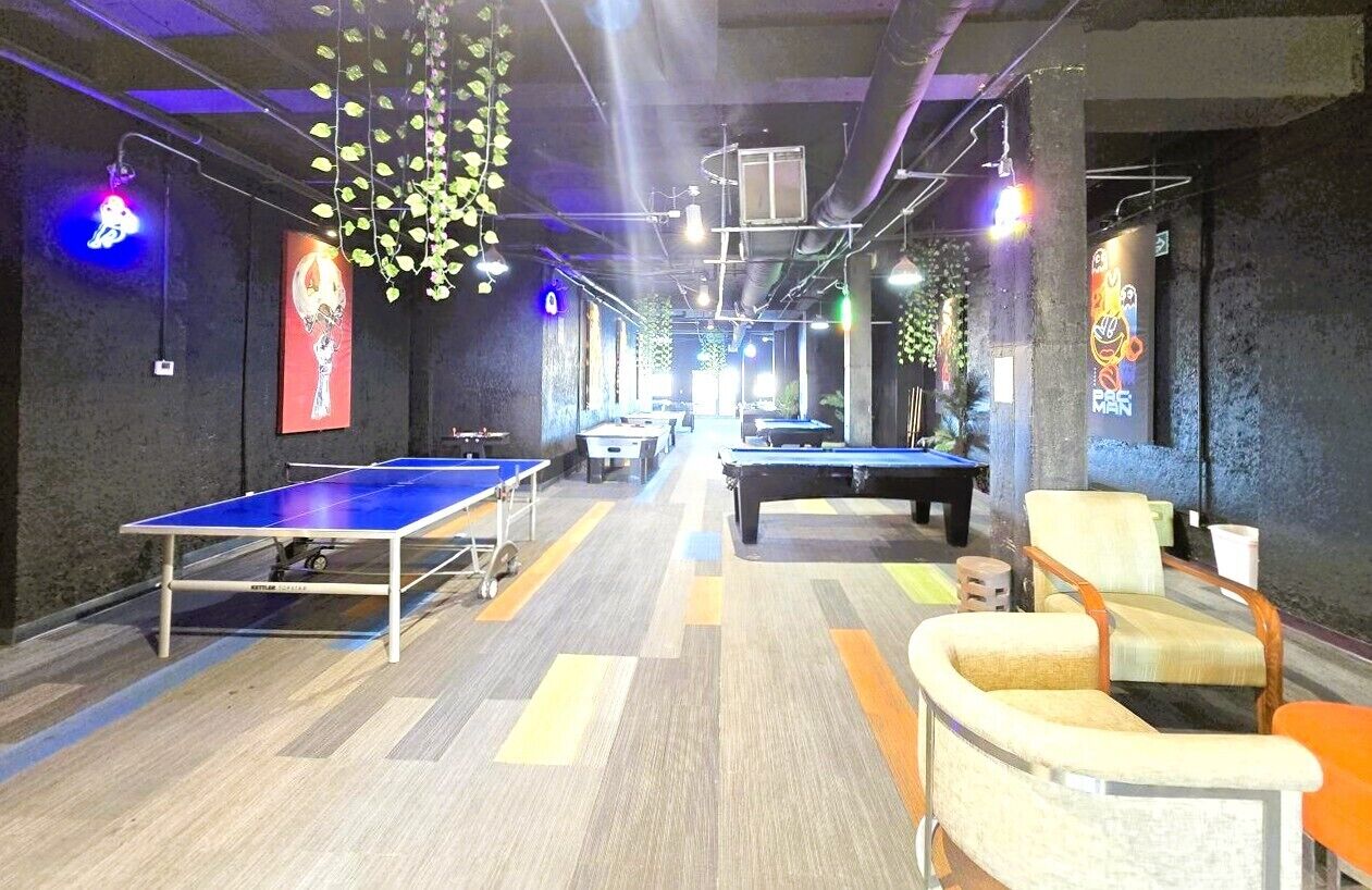 A billiards room with tables, chairs, and hanging plants.