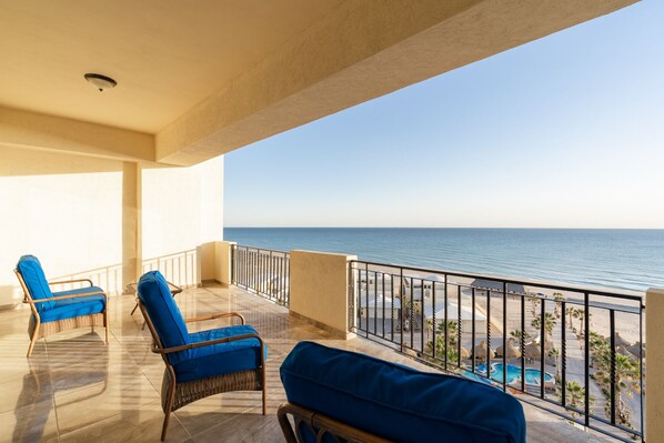 A balcony with two wicker chairs and a pool view. - Luxury Condo Fully Furnished Balcony C-30608 (Puerto Peñasco)