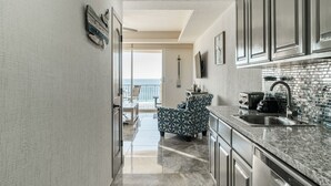 Una cucina con vista sul balcone, un'area pranzo con sedie e un bancone con lavello ed elettrodomestici.