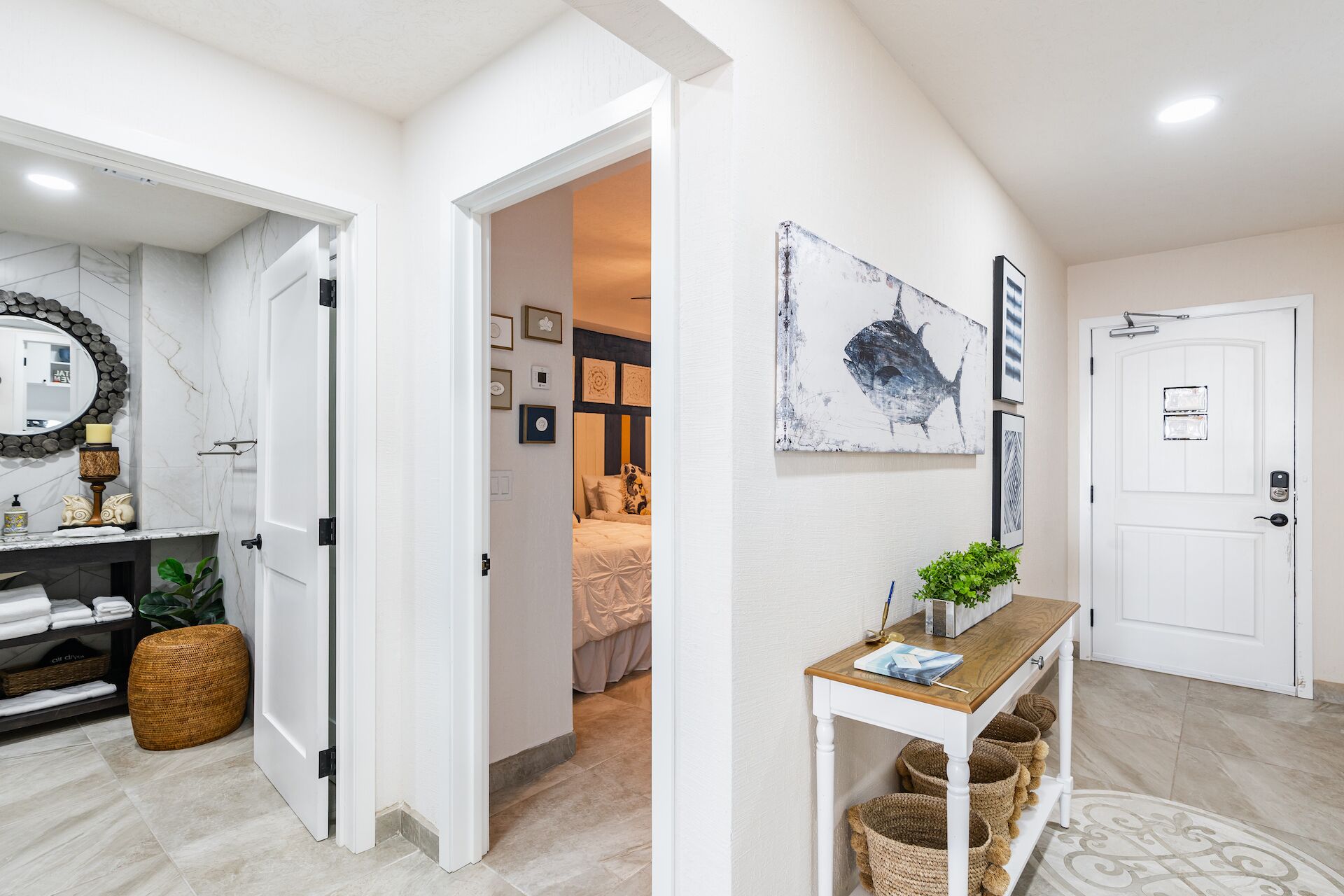 Een modern interieur met een gang die leidt naar een slaapkamer, een witte deur en een tafel met manden.
