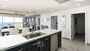 Une cuisine moderne dotée d’un grand îlot central, d’un lave-vaisselle et offrant une vue sur l’extérieur.