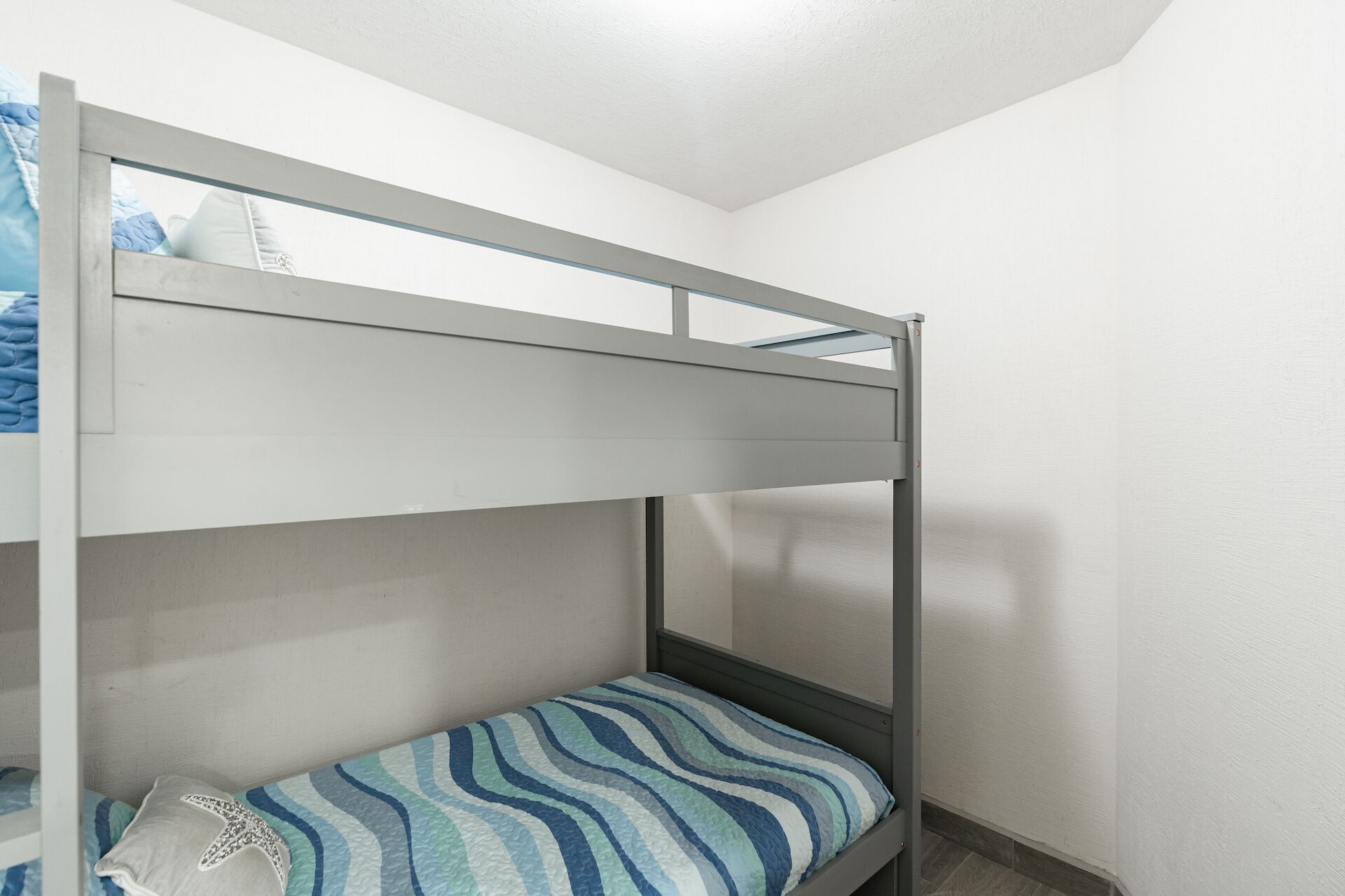 A bunk bed with a striped mattress in a room with white walls and a sloped ceiling.