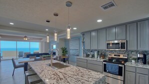 Una cocina moderna con una isla grande, electrodomésticos de acero inoxidable y vistas al exterior.