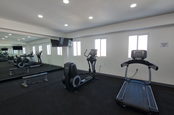 A gym with treadmills, elliptical machines, and a bench.