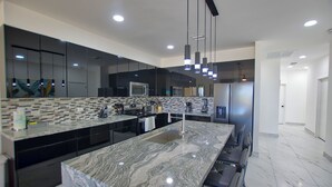 A modern kitchen with a large island, stainless steel appliances, and pendant lighting. - Great capacity 5 bedroom condo D-40110 (Puerto Peñasco)