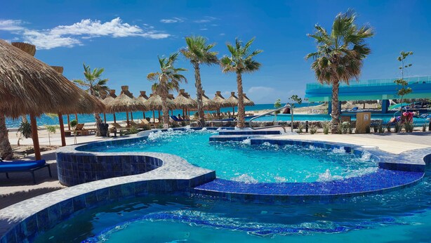 A pool area with multiple water features, palm trees, and lounge chairs. - Great capacity 5 bedroom condo D-40110 (Puerto Peñasco)