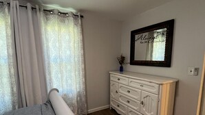 Une chambre à coucher avec un lit, une commode, un miroir et un ventilateur de plafond.