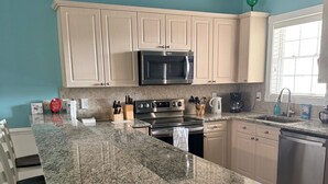 A kitchen with granite countertops, stainless steel appliances, and light-colored cabinetry.