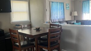 Un comedor con una mesa y sillas, un ventilador de techo y una ventana con persianas.
