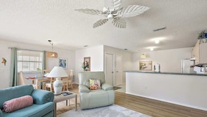 A modern living room with a sofa, armchair, and a dining area with a table and chairs.