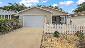 A single-story house with a garage, a covered porch, and a white picket fence.